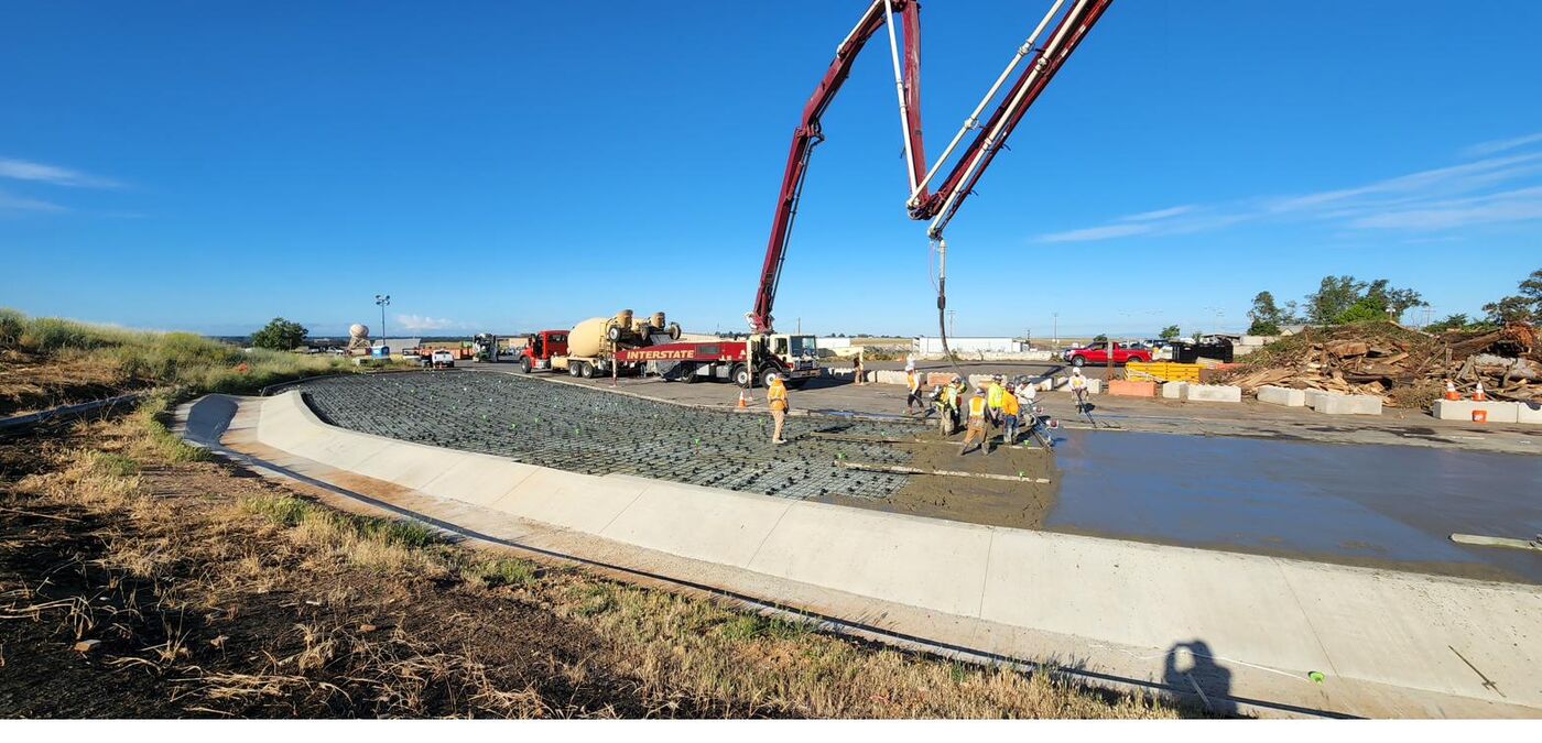 Crew screeding fresh concrete on a large infrastructure slab