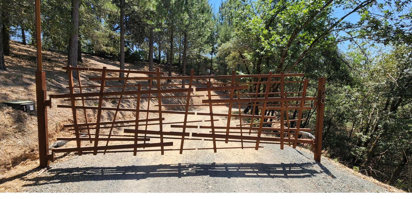 Custom corten-steel entrance gate at a forest driveway